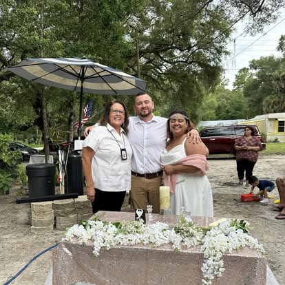 Esther with a couple at an outdoor reception