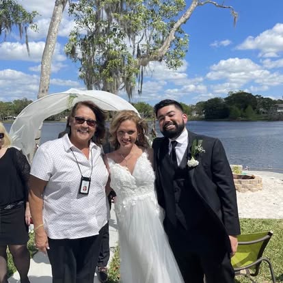 Esther with newlyweds beside a waterfront arbor