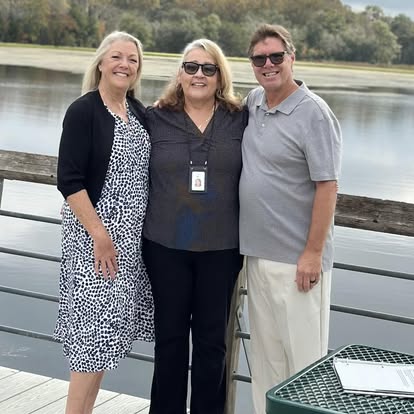 Esther with a couple beside a swimming pool