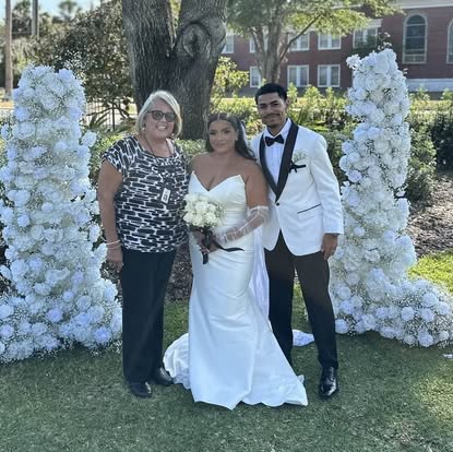 Esther with newlyweds beside white floral decorations