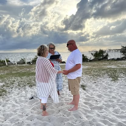 A couple exchanging vows on the beach at sunset