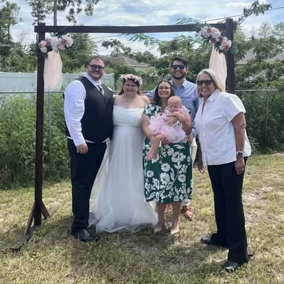 Esther and a wedding party beneath a floral arbor