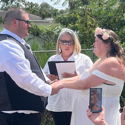 Esther reading a ceremony script to a couple outdoors