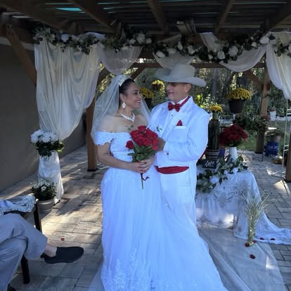Newlyweds beneath a decorated outdoor shelter