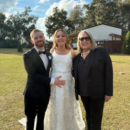 Esther with newlyweds outside a white building